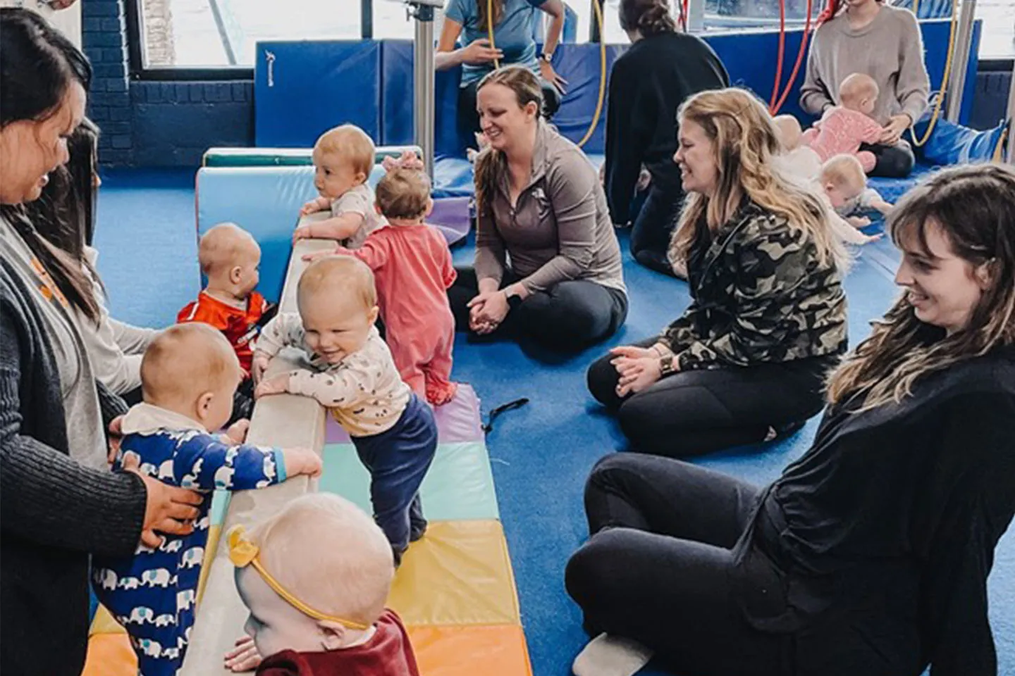 Parents and babies playing together on the mat in a baby class