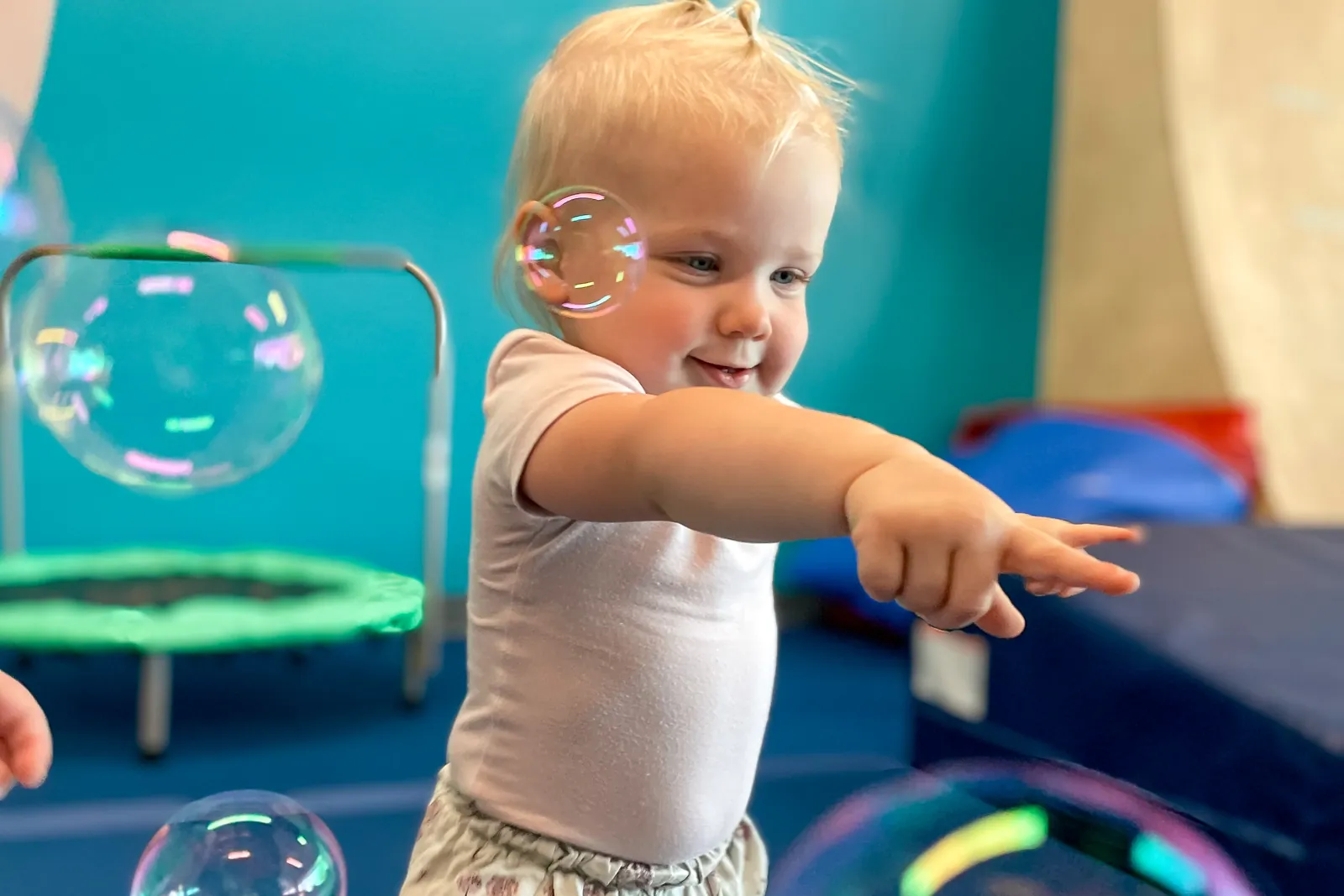 A toddler pointing at bubbles in the gym