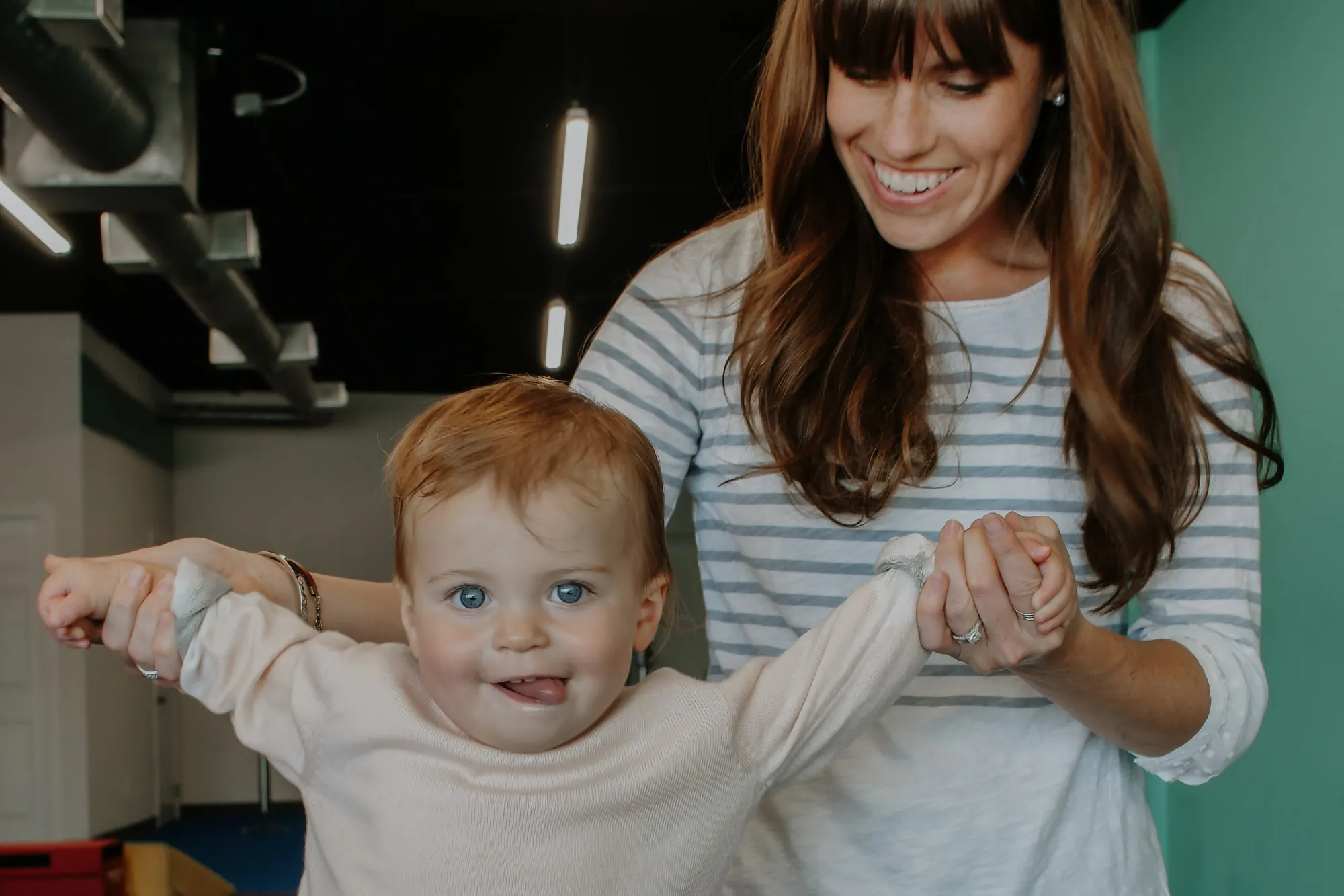 A mom helping her baby stand during a parent and child class