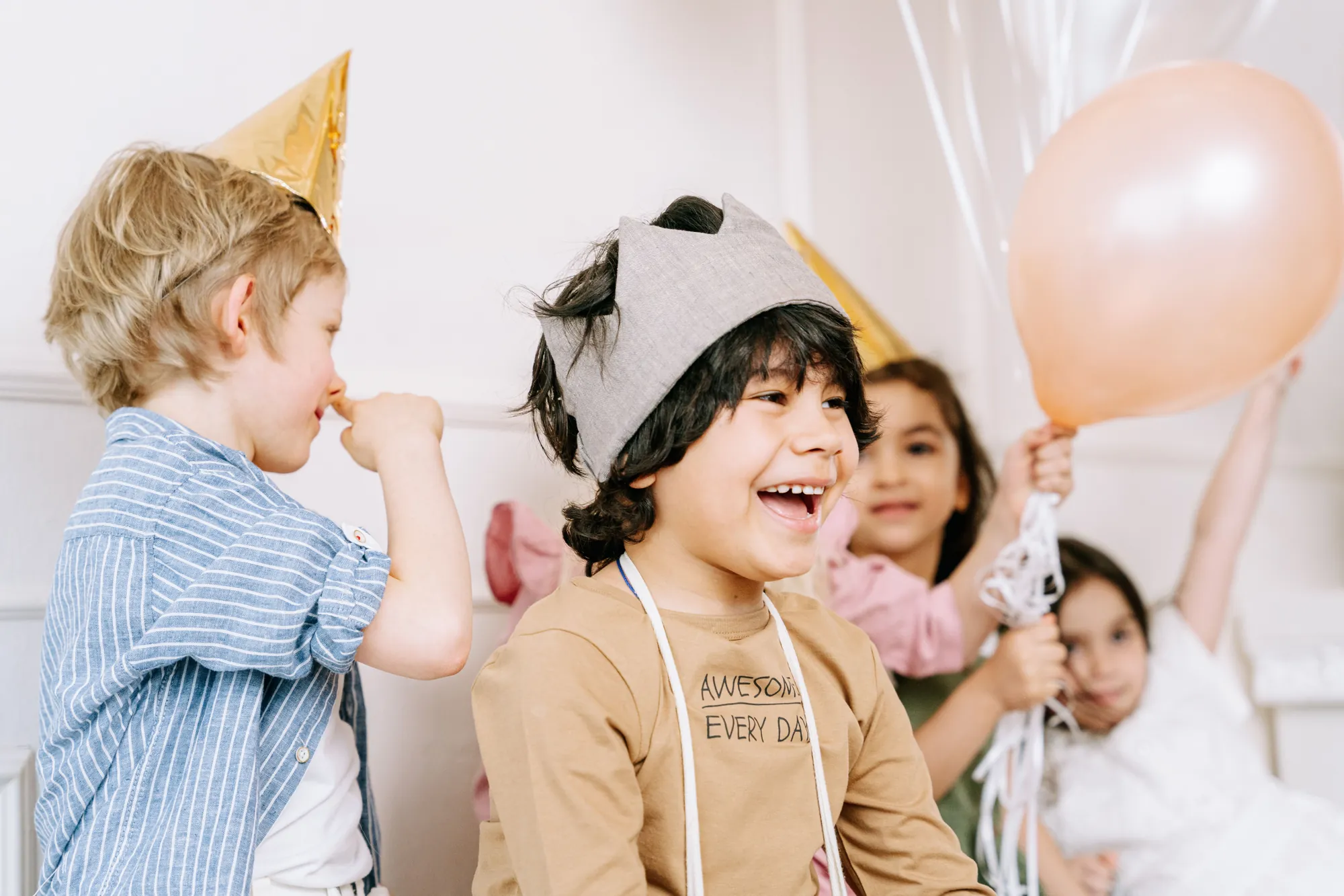 Kids in party hats laughing together at a birthday party