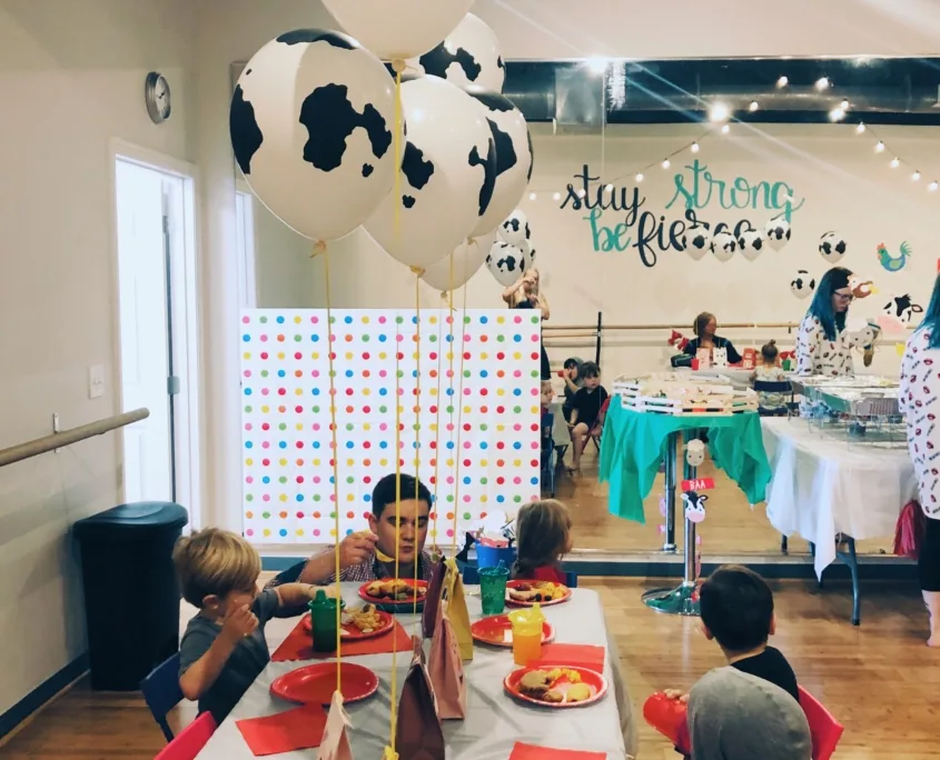 Kids eating at a decorated birthday table inside the gym