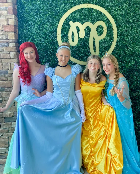 Princess characters in front of the Modern Play neon sign