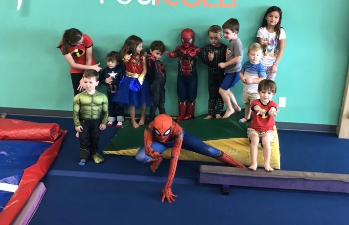 Spiderman posing with a group of excited kids at a Modern Play birthday party